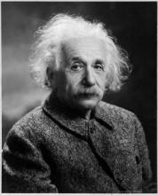 A black and white photo of Albert Einstein.  He has a mustache and disheveled white hair.