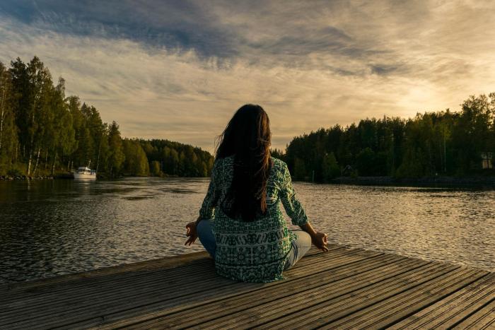Woman practicing mindful meditation near a lake